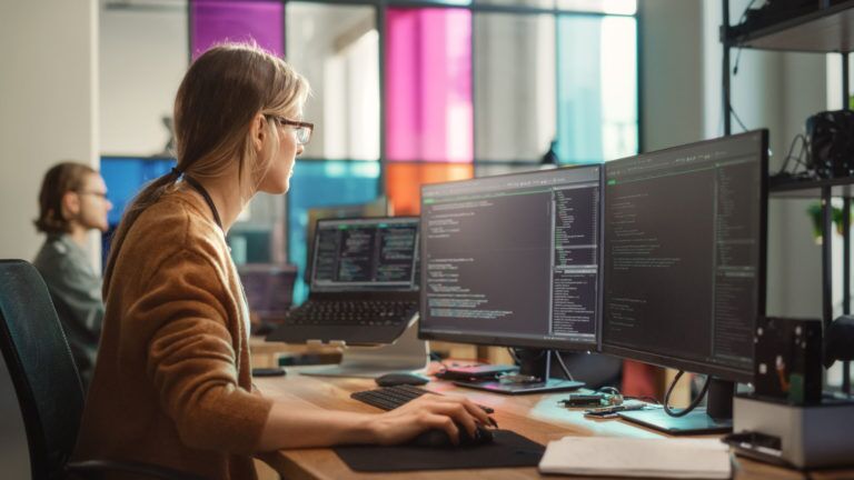 Female Software Engineer Writing Code on Desktop Computer with M